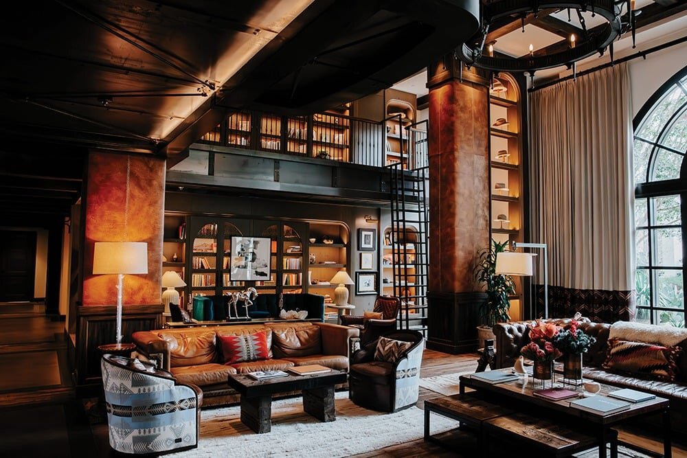Hotel Drover lobby — leather sofas, stone columns, library, and arched windows